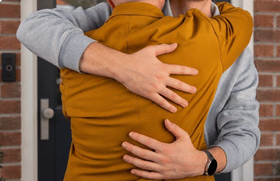 Twee mensen omhelzen elkaar bij de voordeur